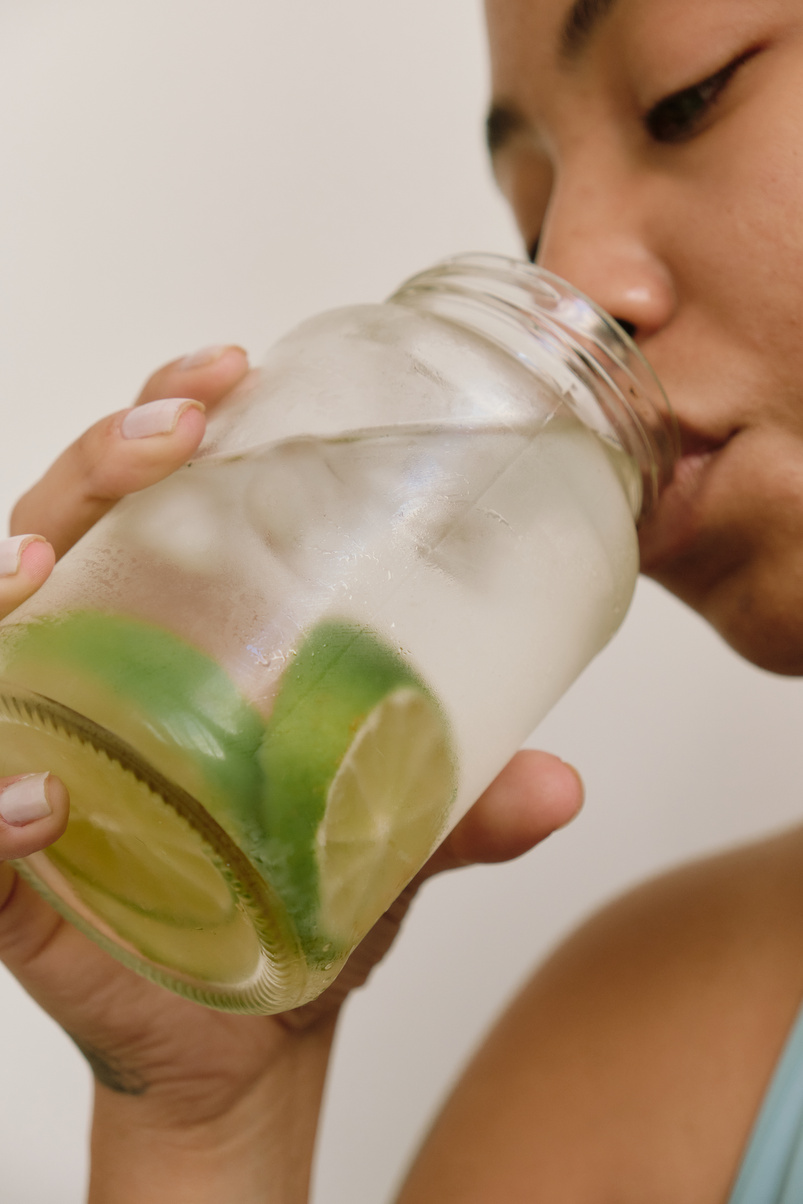 Woman Drinking a Glass of Cold Water with Lime Slices